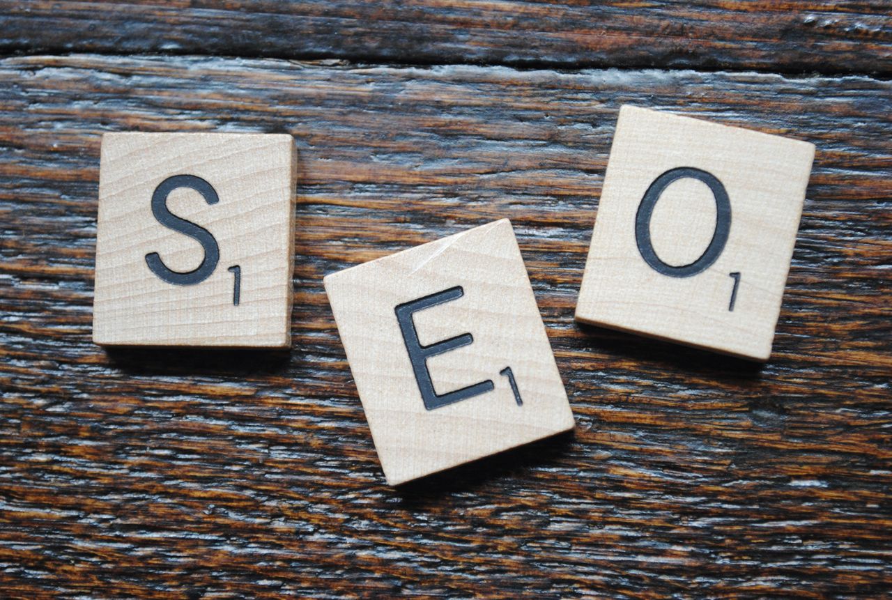 Gros plan sur des lettres de Scrabble formant SEO sur une table en bois pour la stratégie de contenu.